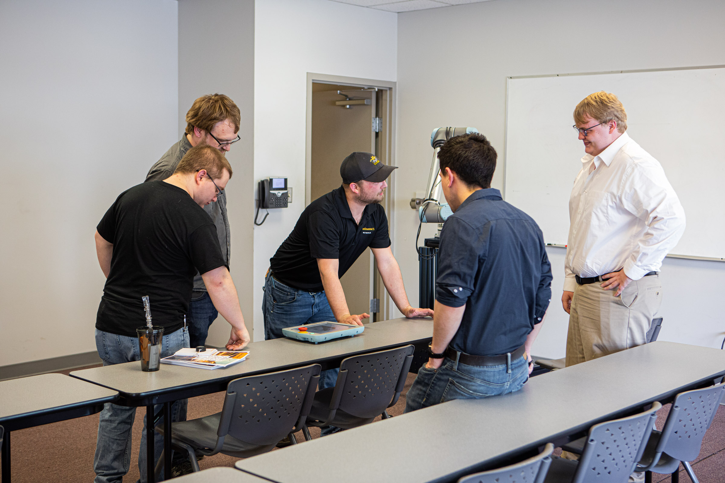 Continental Tire's Systems Specialist, Aubreylee Jones, shows current RLC students the controller for the robot at the ICATT open house event.