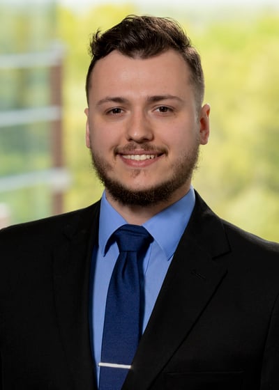 Professional headshot of Rend Lake College alumnus Cody Sissom smiling, wearing a dark suit, blue dress shirt, and blue tie.
