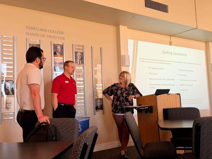 Three Banterra Bank representatives—Jared Leslie, Aaron Fitzgerrel, and Amy Wilton—stand near a podium presenting a financial management workshop with a slide detailing "Banking Convenience" options.