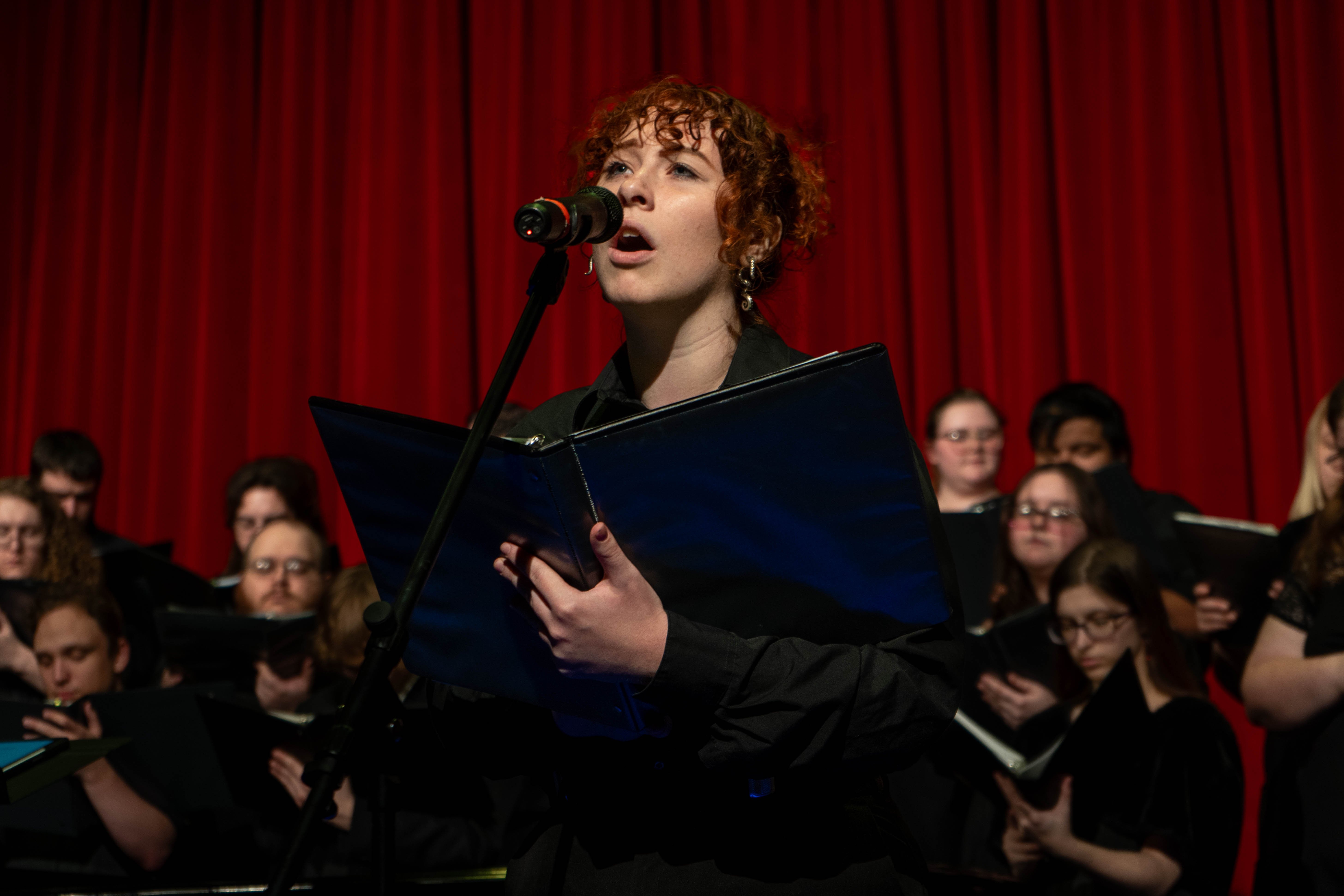 Jinx Craddock sings into a microphone during the 2026 Spring Concert: Chiaroscuro.