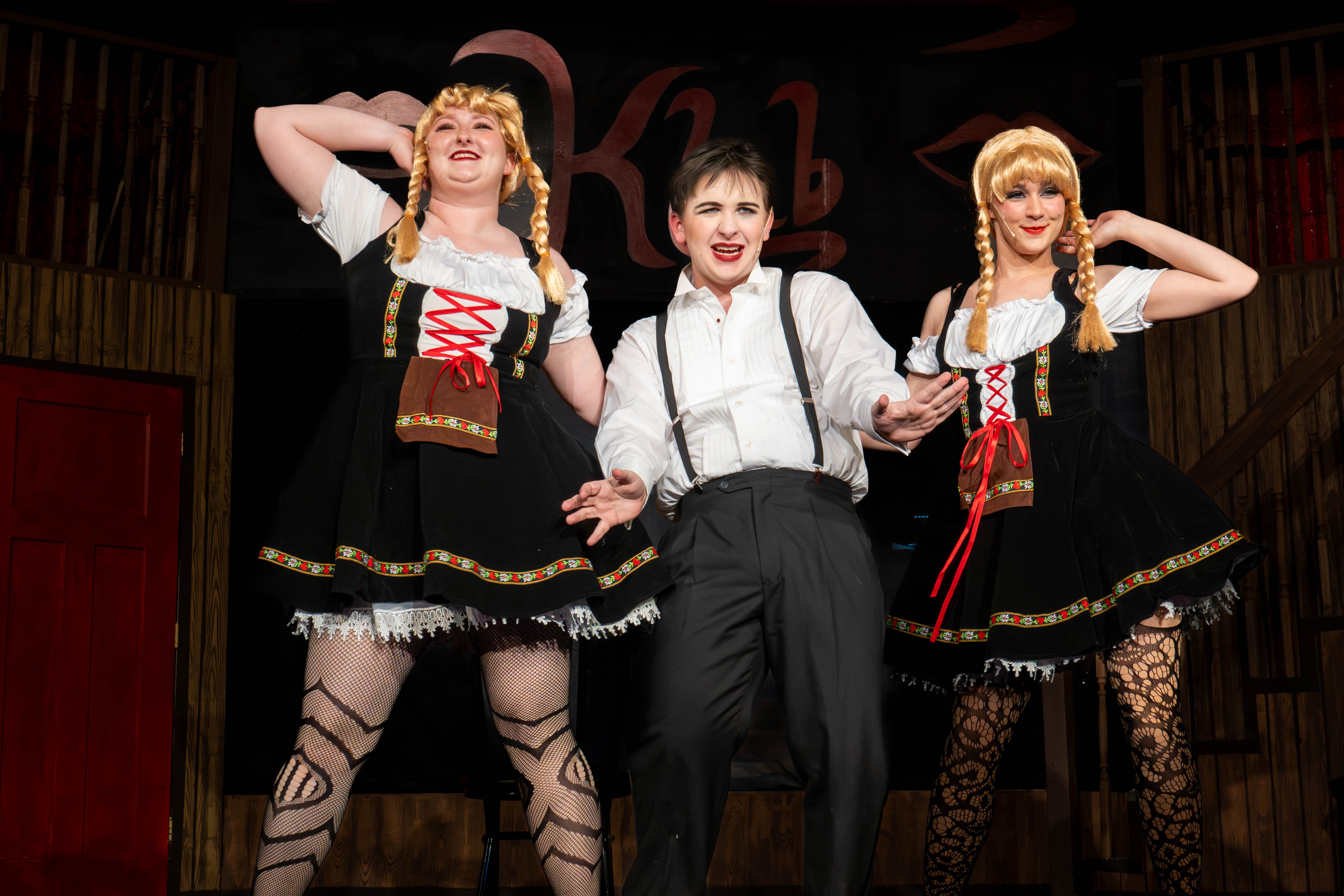 Holdyn Westberry as the Emcee stands center stage, flanked by two Kit Kat Girls, Alexandria Galyean (left) and Madison Brower (right), during a performance of Cabaret.